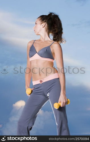 Low angle view of a young woman holding dumbbells