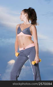 Low angle view of a young woman holding dumbbells