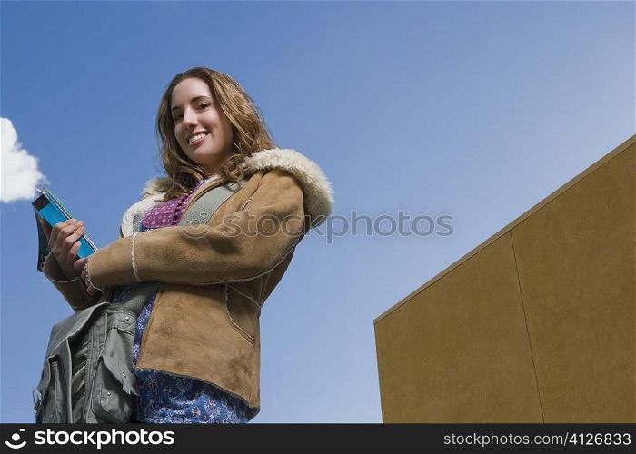 Low angle view of a young woman holding textbooks