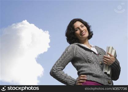 Low angle view of a young woman holding textbooks