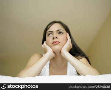 Low angle view of a young woman lying on the bed and thinking