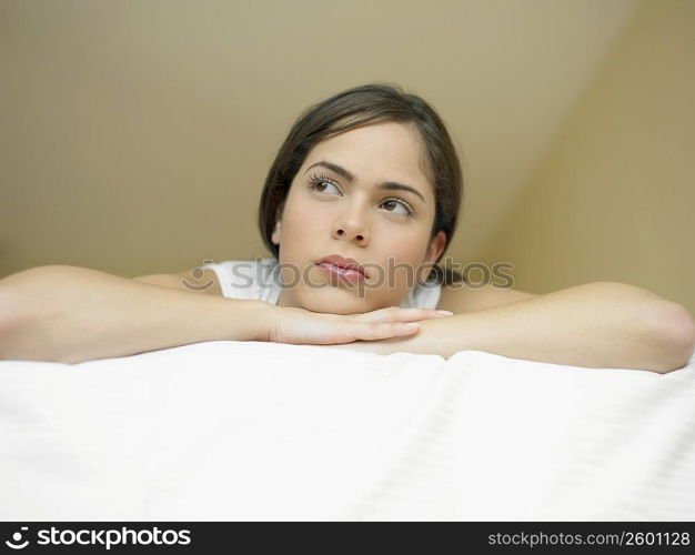 Low angle view of a young woman lying on the bed and thinking