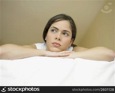 Low angle view of a young woman lying on the bed and thinking