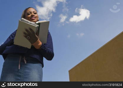 Low angle view of a young woman reading a textbook