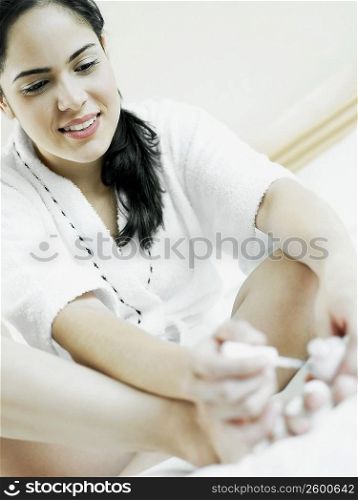 Low angle view of a young woman sitting and polishing her nail with nail polish