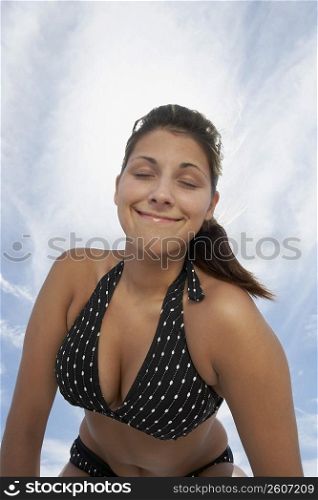 Low angle view of a young woman smirking with her eyes closed