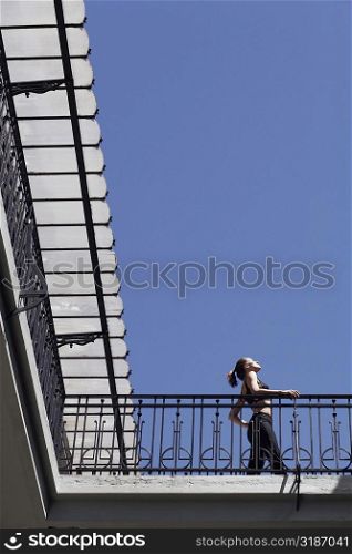 Low angle view of a young woman standing in the balcony of a building