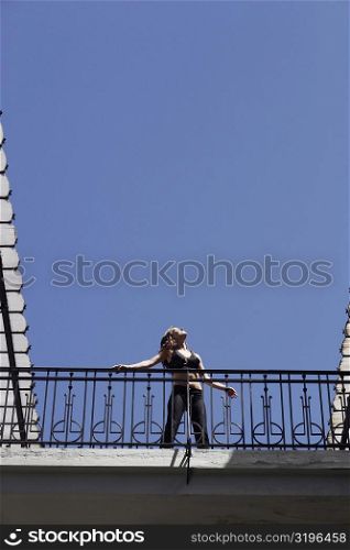 Low angle view of a young woman standing in the balcony of a building