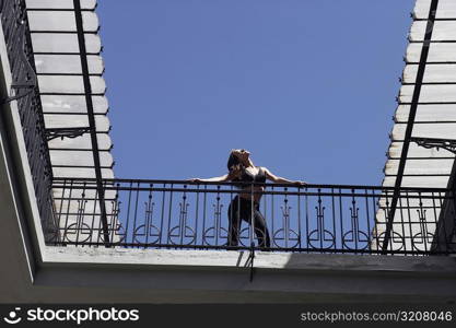 Low angle view of a young woman standing in the balcony of a building