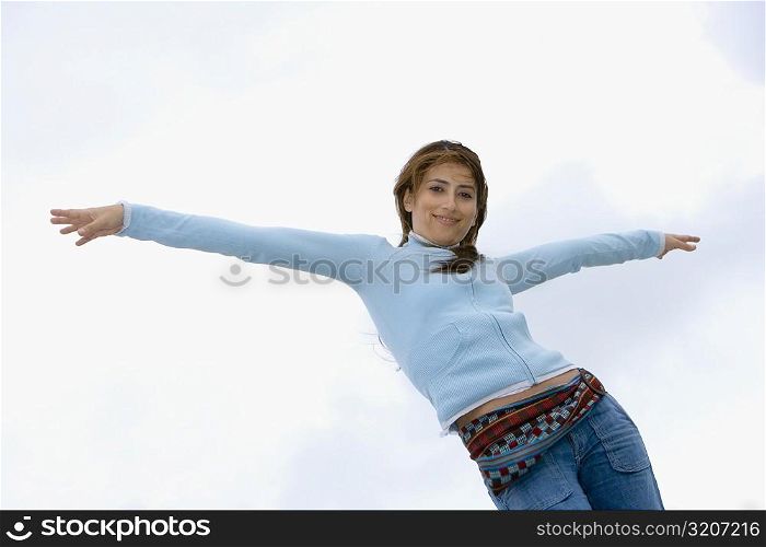 Low angle view of a young woman standing with her arms outstretched