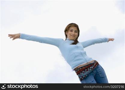 Low angle view of a young woman standing with her arms outstretched