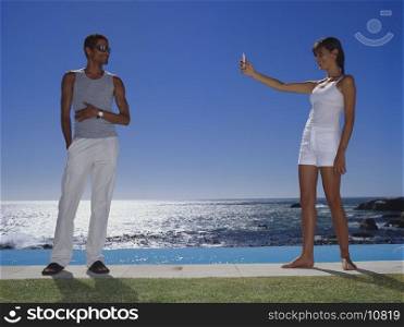 Low angle view of a young woman taking a picture of a young man with a mobile phone