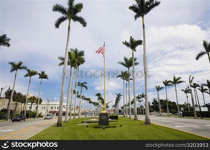 Low angle view of an American flag with palm trees, Royal Poinciana Way, Palm Beach, Florida, USA