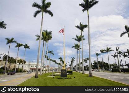Low angle view of an American flag with palm trees, Royal Poinciana Way, Palm Beach, Florida, USA