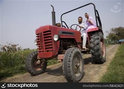 Low angle view of an Indian couple sitting in a tractor