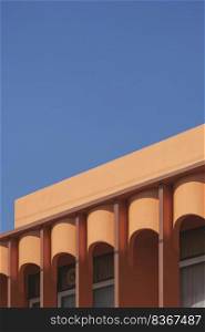 Low angle view of arches wall of colonnade orange house against blue clear sky in vintage tone style and vertical frame