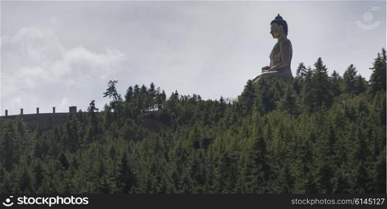 Low angle view of Buddha Dordenma Statue surrounded by trees, Thimphu, Bhutan