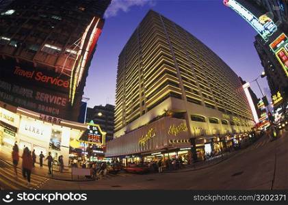Low angle view of buildings in a city lit up at night, Hong Kong, China