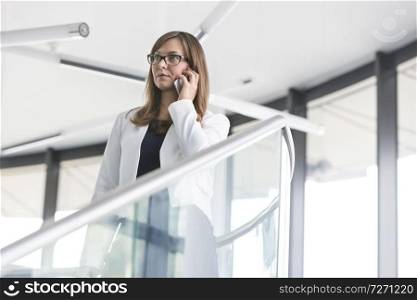 Low angle view of businesswoman talking on smartphone while standing at office