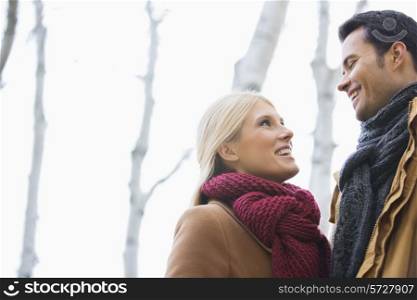Low angle view of couple looking at each other in park during autumn