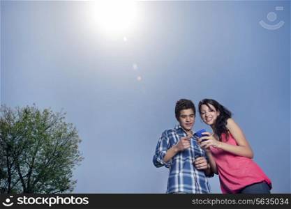 Low angle view of couple smiling and looking at mobile phone
