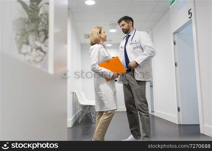 Low angle view of doctors discussing in corridor at hospital