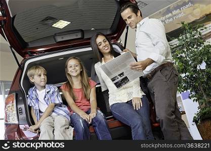 Low angle view of family sitting at back of car