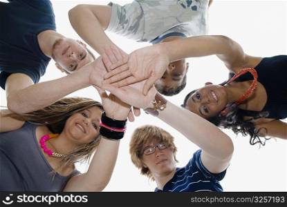 Low angle view of five friends stacking their hands