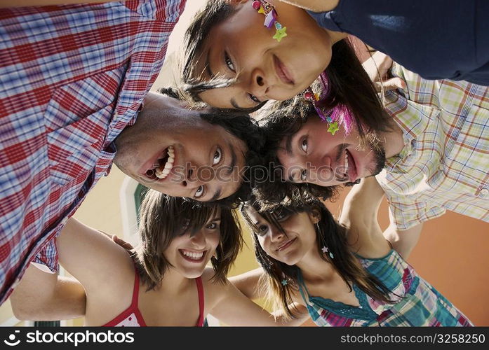 Low angle view of five friends standing in a huddle and smiling