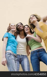 Low angle view of four teenage girls pointing up