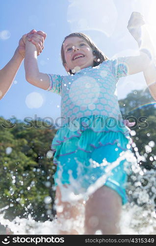 Low angle view of girl holding hands and running in sea, Hot Water Beach, Bay of Islands, New Zealand