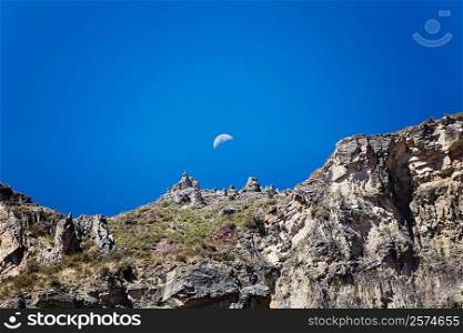 Low angle view of half moon over a rocky mountain, Chivay, Arequipa, Peru
