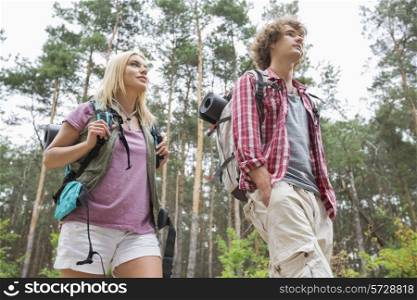 Low angle view of hiking couple looking away in forest
