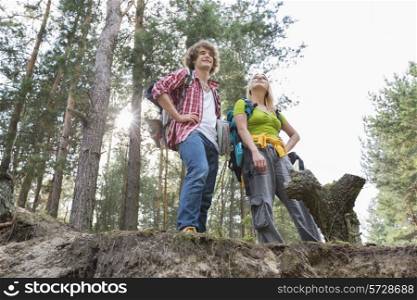 Low angle view of hiking couple standing on cliff in forest