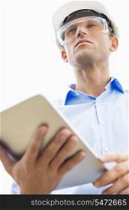 Low angle view of male architect holding tablet PC against sky