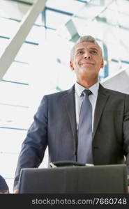 Low angle view of mature businessman queuing for check in at airport