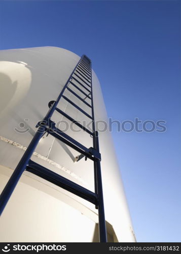 Low angle view of metal grain storage silo with ladder assending to top.