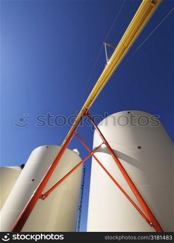 Low angle view of metal grain storage silos against blue background.