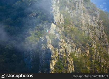 Low angle view of Mexican flag fluttering on a mountain, Waterfalls of the Monkeys, City Valleys, San Luis Potosi, Mexico