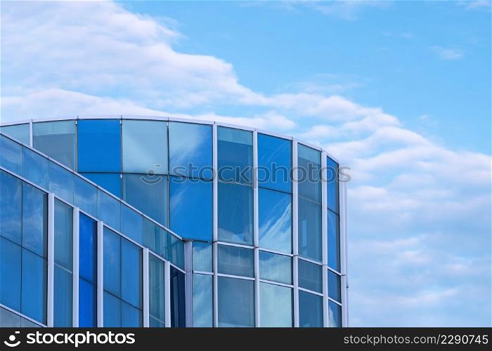 Low angle view of modern blue glass office building against white clouds in blue sky background, manipulation techniques