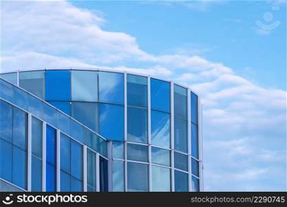 Low angle view of modern blue glass office building against white clouds in blue sky background, manipulation techniques