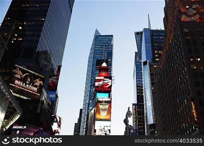 Low angle view of skyscrapers and advertising signs at sunset, New York, USA