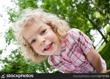 Low angle view of smiling child standing in spring park. Shot was taken with fisheye lens