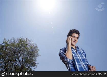 Low angle view of smiling young man with mobile phone