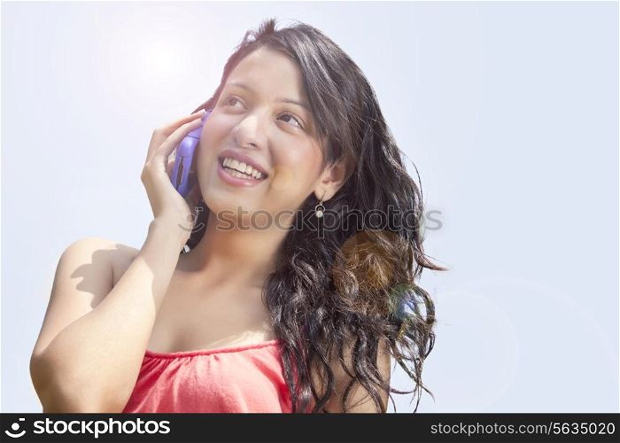 Low angle view of smiling young woman having conversation on mobile phone