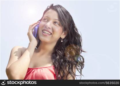 Low angle view of smiling young woman having conversation on mobile phone