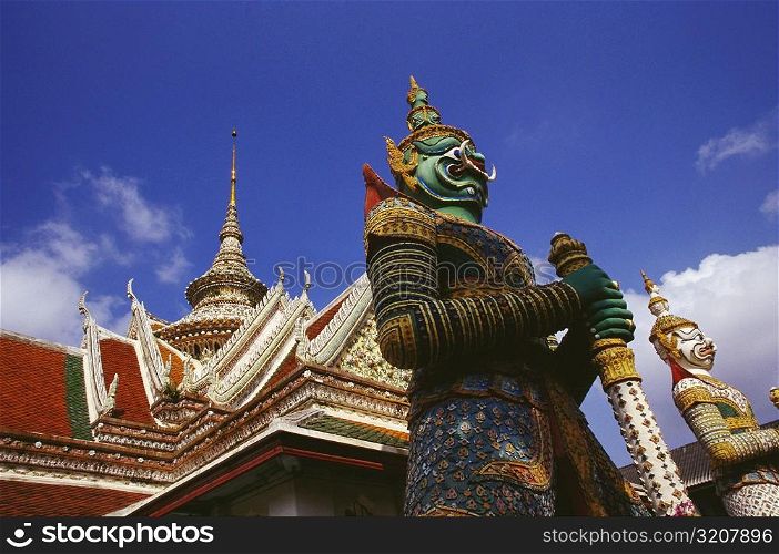 Low angle view of statues in front of a temple, Wat Arun, Bangkok, Thailand
