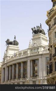 Low angle view of statues on top of a building, Madrid, Spain