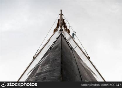 Low angle-view of the bow of a wooden luxury sail boat against a cloudy sky.