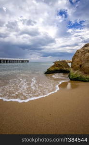 Low angle view of the sea with a pier and big rock on shore